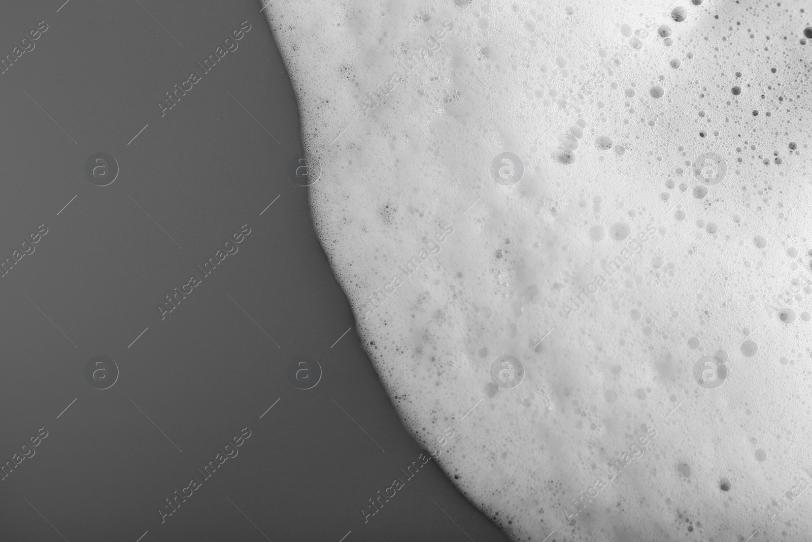 Photo of White foam with bubbles on grey background, top view. Space for text