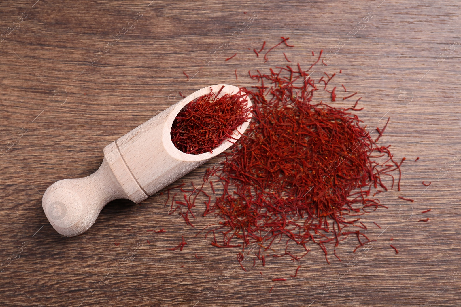 Photo of Aromatic saffron and scoop on wooden table, top view