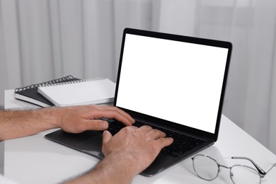 Man using laptop at white table indoors, closeup