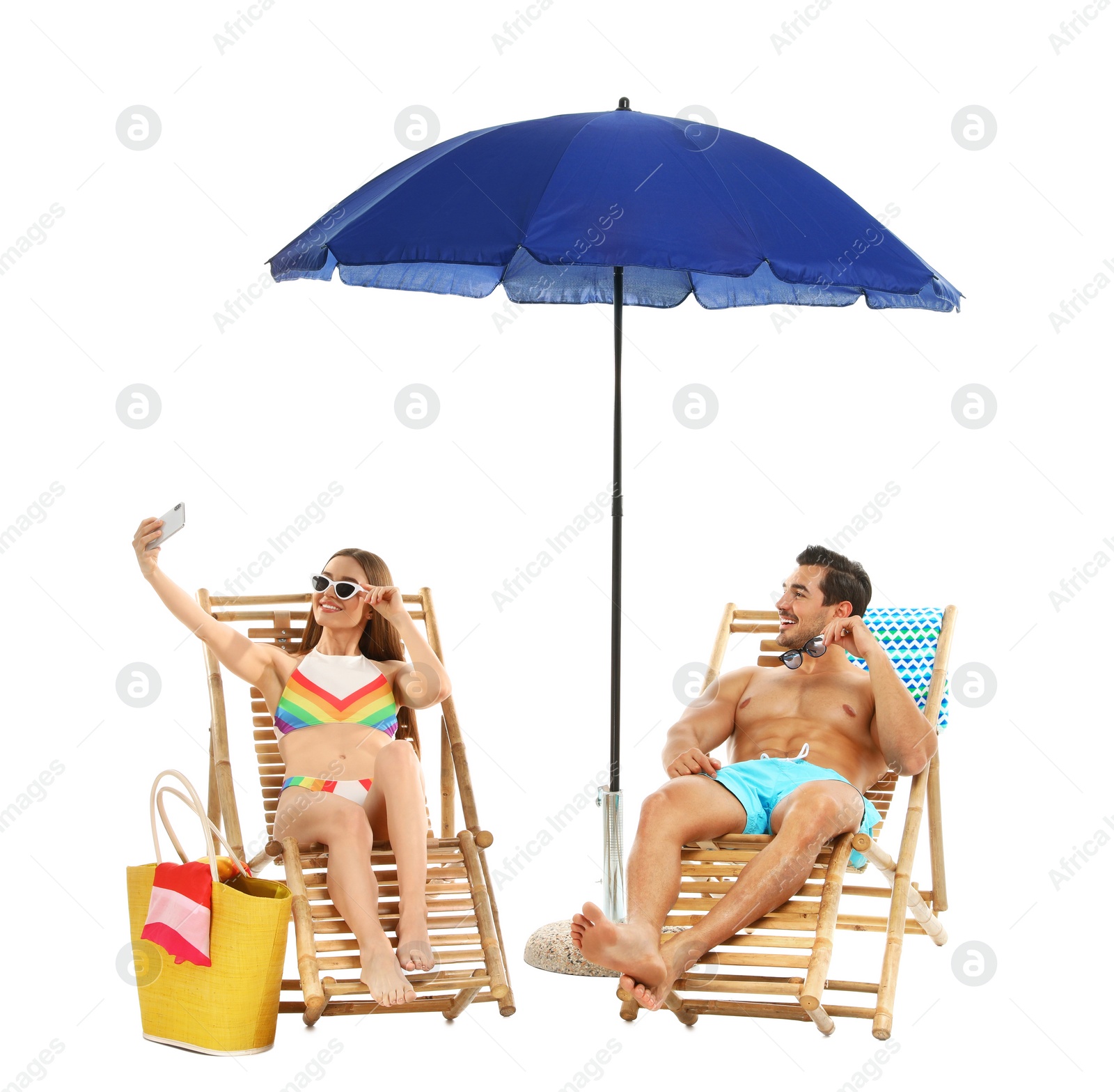 Photo of Young couple taking selfie on sun loungers under umbrella against white background. Beach accessories