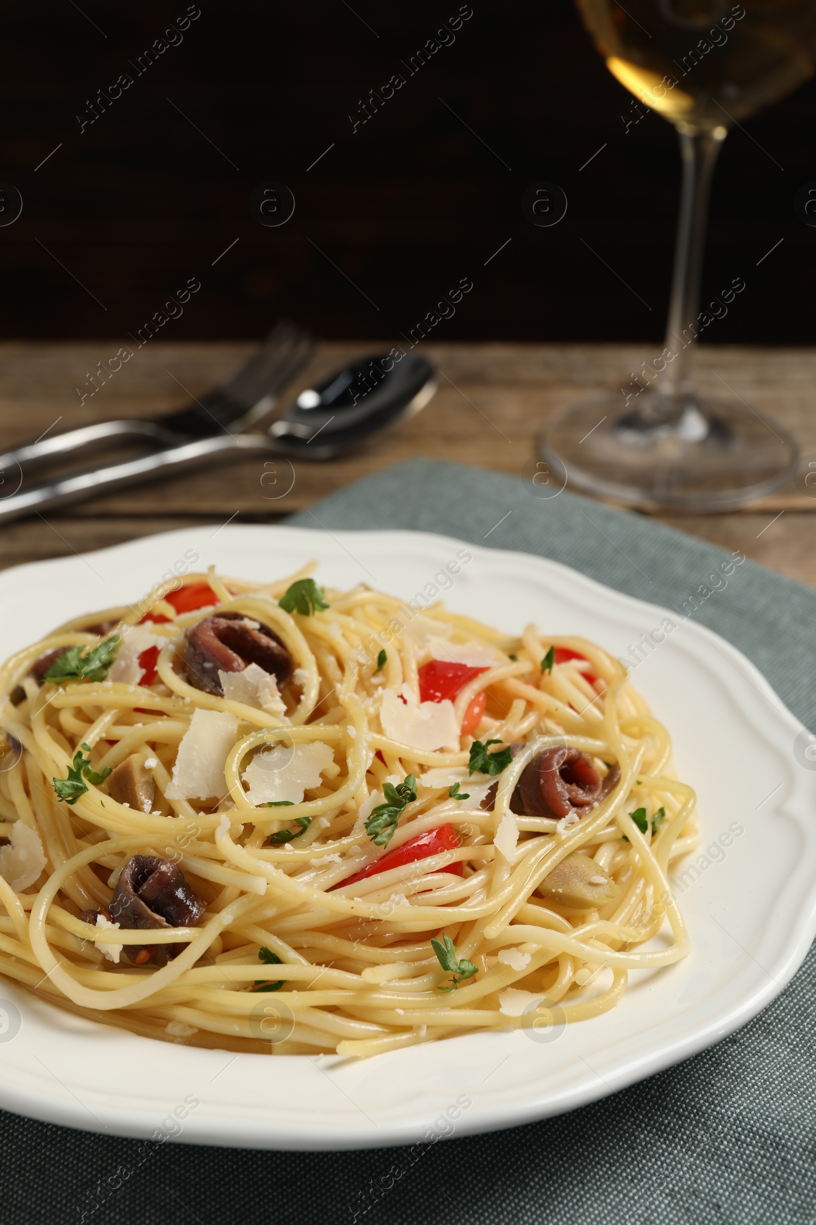 Photo of Delicious pasta with anchovies, tomatoes and parmesan cheese on table