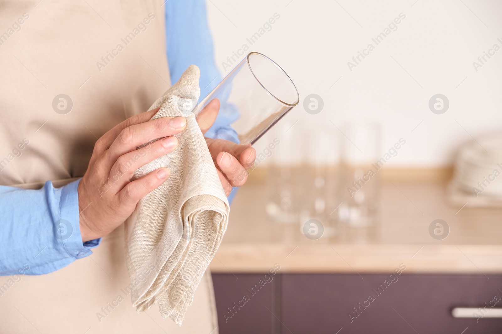 Photo of Woman wiping glass with towel in kitchen, closeup. Space for text