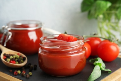 Composition with tomato sauce in jars on table