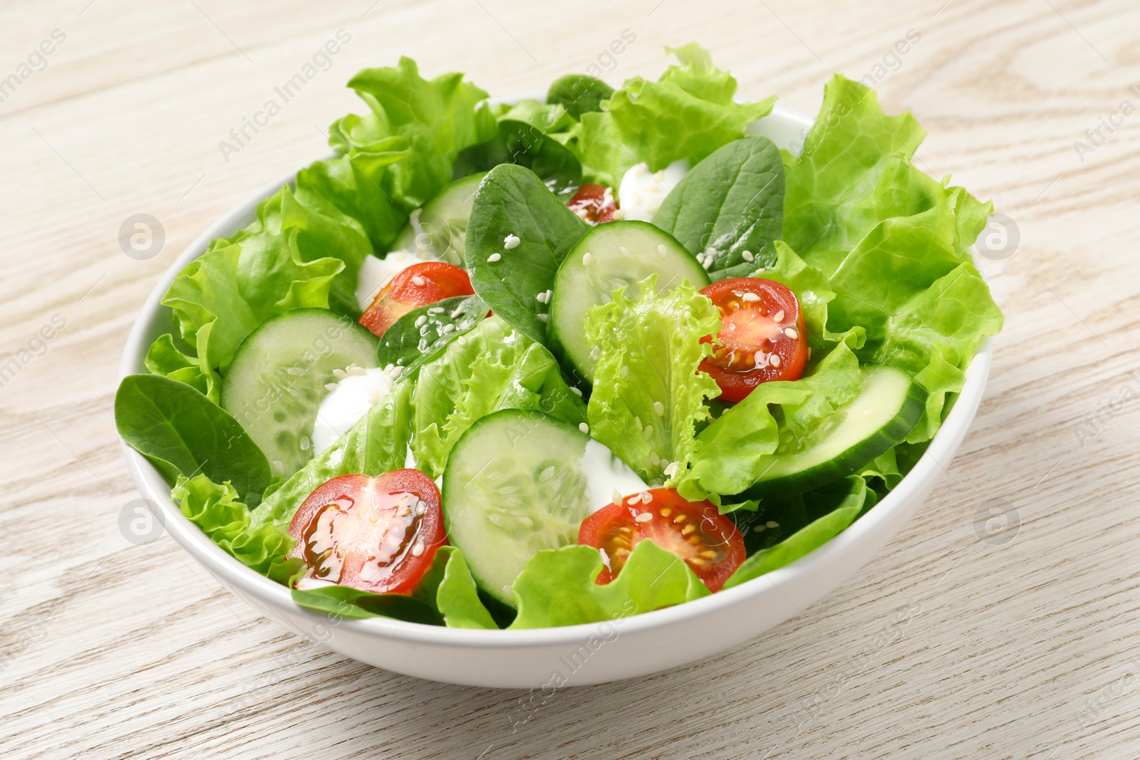 Photo of Delicious salad in bowl on white wooden table