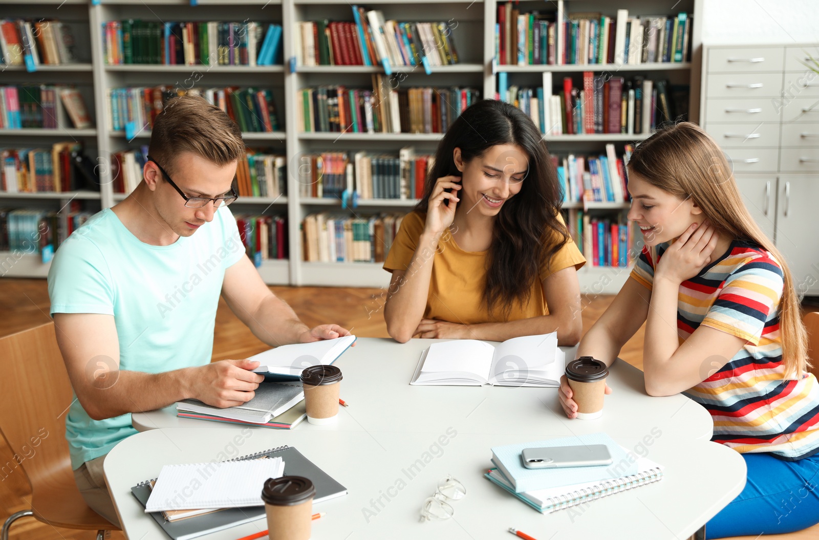 Photo of Young people discussing group project at table in library