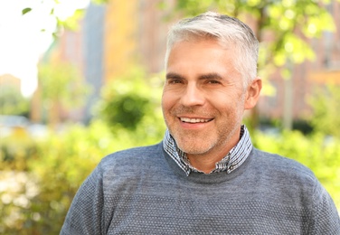 Photo of Portrait of handsome mature man in park. Space for text