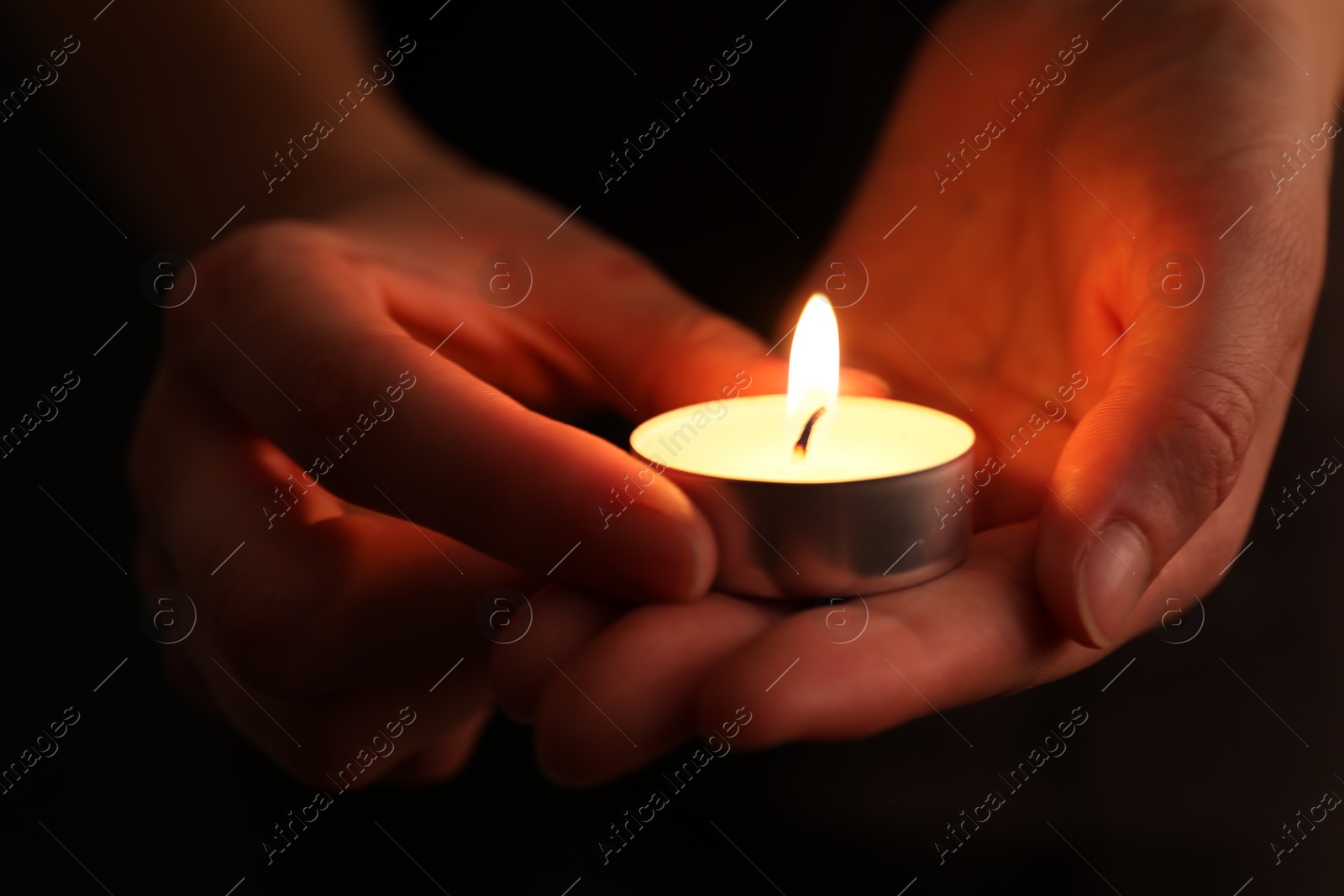 Photo of Woman with burning candle in darkness, closeup. Memory day