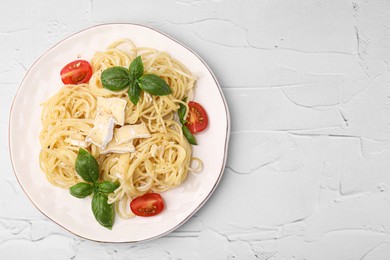 Photo of Delicious pasta with brie cheese, tomatoes and basil leaves on white textured table, top view. Space for text