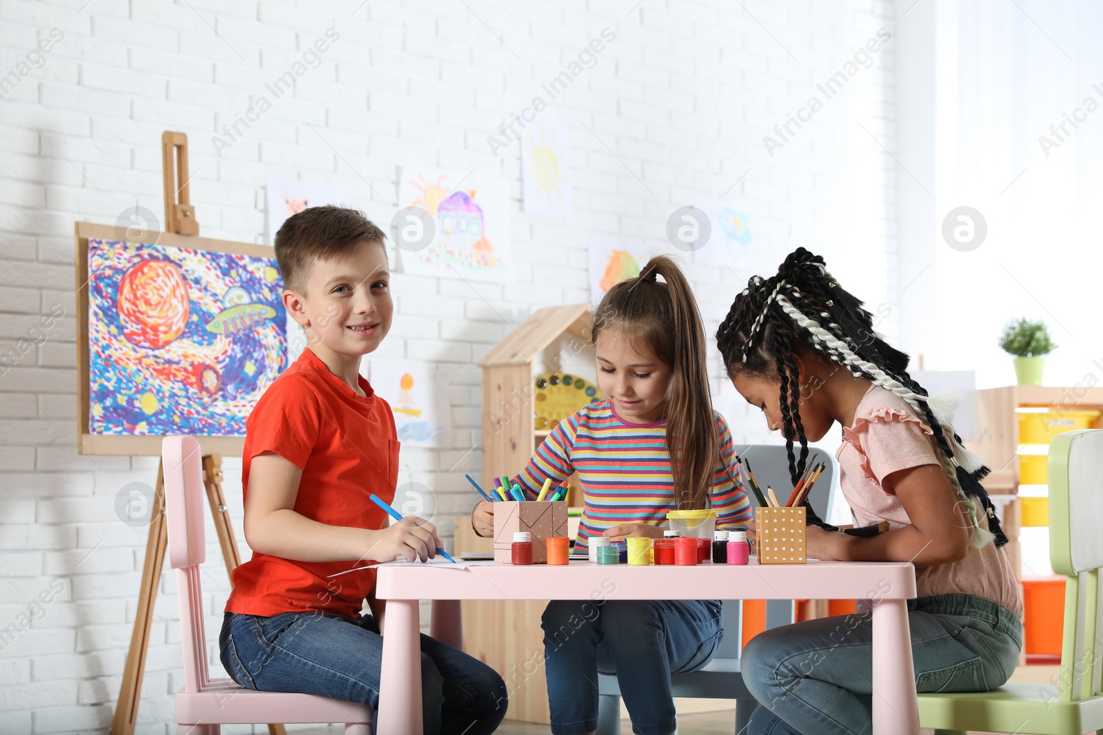 Photo of Cute little children drawing at painting lesson indoors