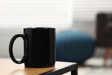 Photo of Black mug on wooden table indoors. Mockup for design