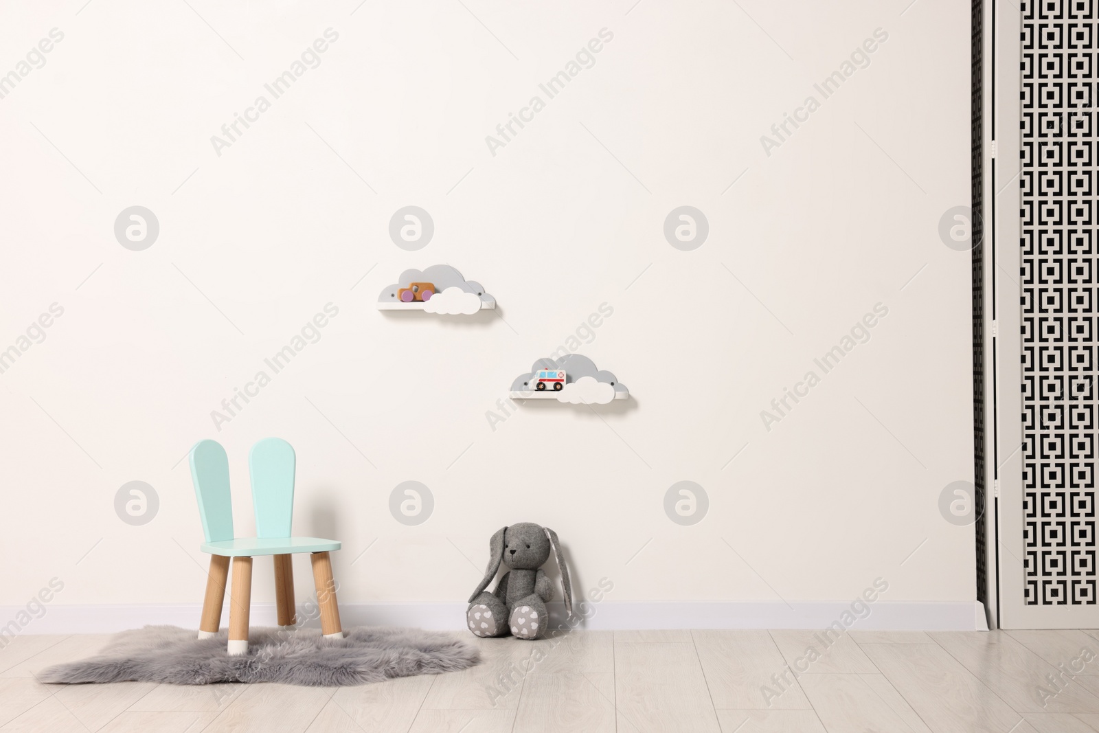 Photo of Beautiful children's room with light wall, chair and toys, space for text. Interior design