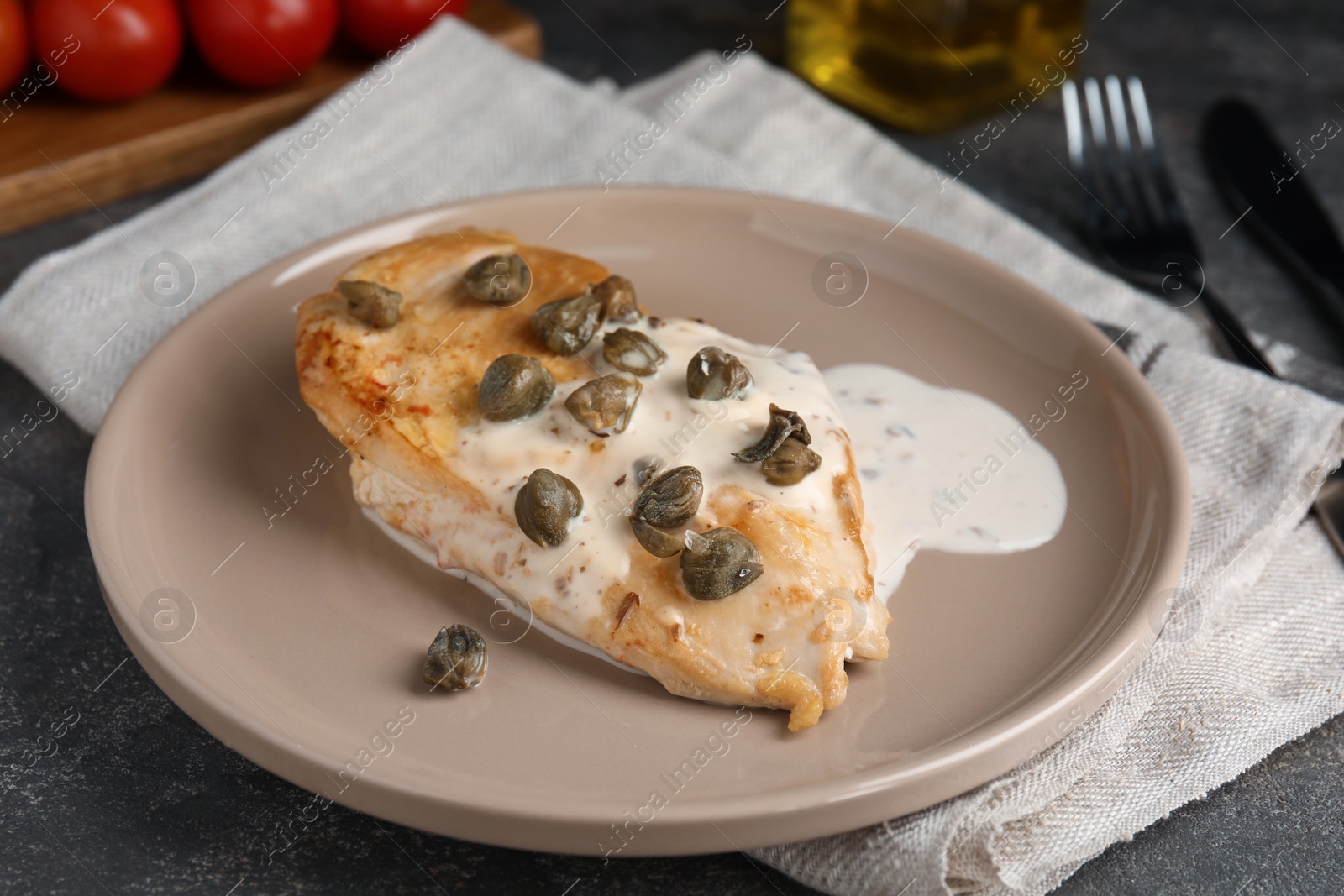 Photo of Delicious chicken fillet with capers and sauce served on grey table, closeup