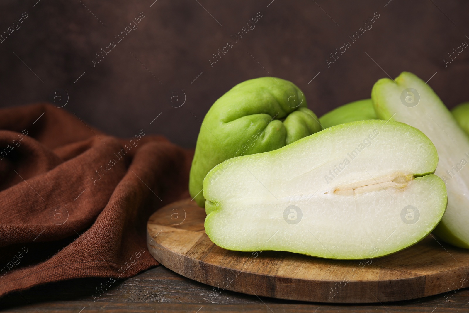 Photo of Cut and whole chayote on wooden table, closeup