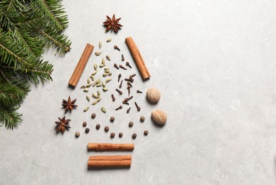 Photo of Christmas tree made of different spices and fir branches on light gray textured table, flat lay. Space for text