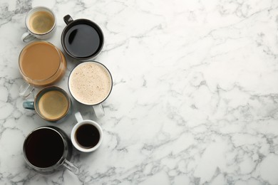 Different coffee drinks in cups on white marble table, flat lay. Space for text