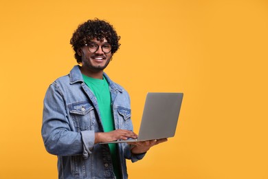 Photo of Smiling man with laptop on yellow background, space for text