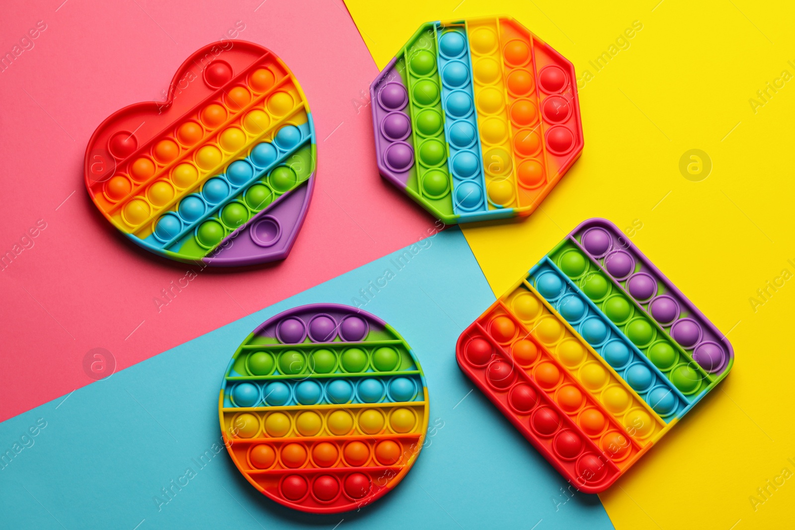 Photo of Rainbow pop it fidget toys on color background, flat lay