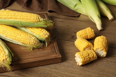 Tasty sweet corn cobs on wooden table