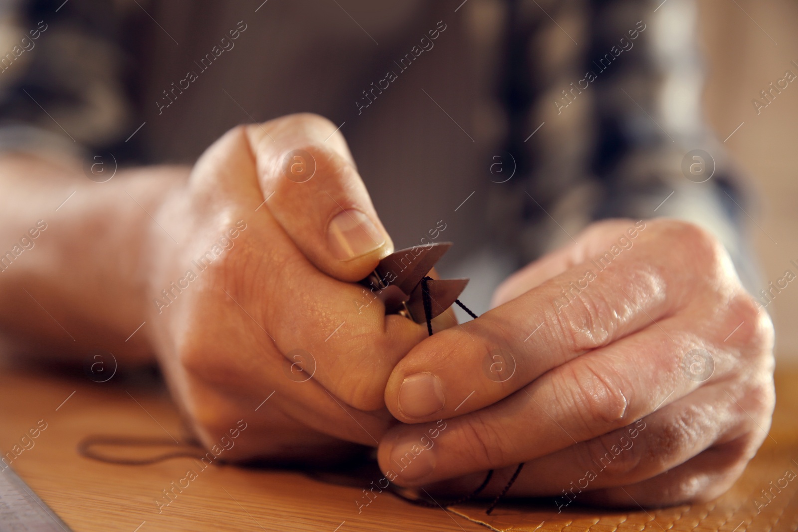 Photo of Man cutting thread while working with leather, closeup