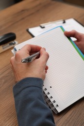 Photo of Man taking notes at wooden table, closeup