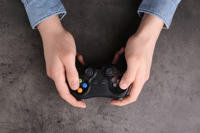 Man using wireless game controller at grey table, top view