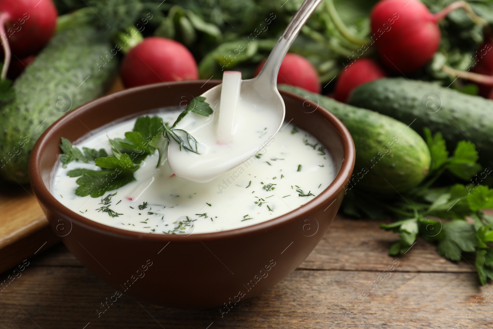 Photo of Delicious cold summer soup with kefir served on wooden table