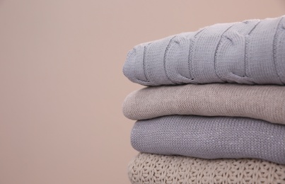 Photo of Stack of folded warm sweaters on grey background, closeup. Space for text