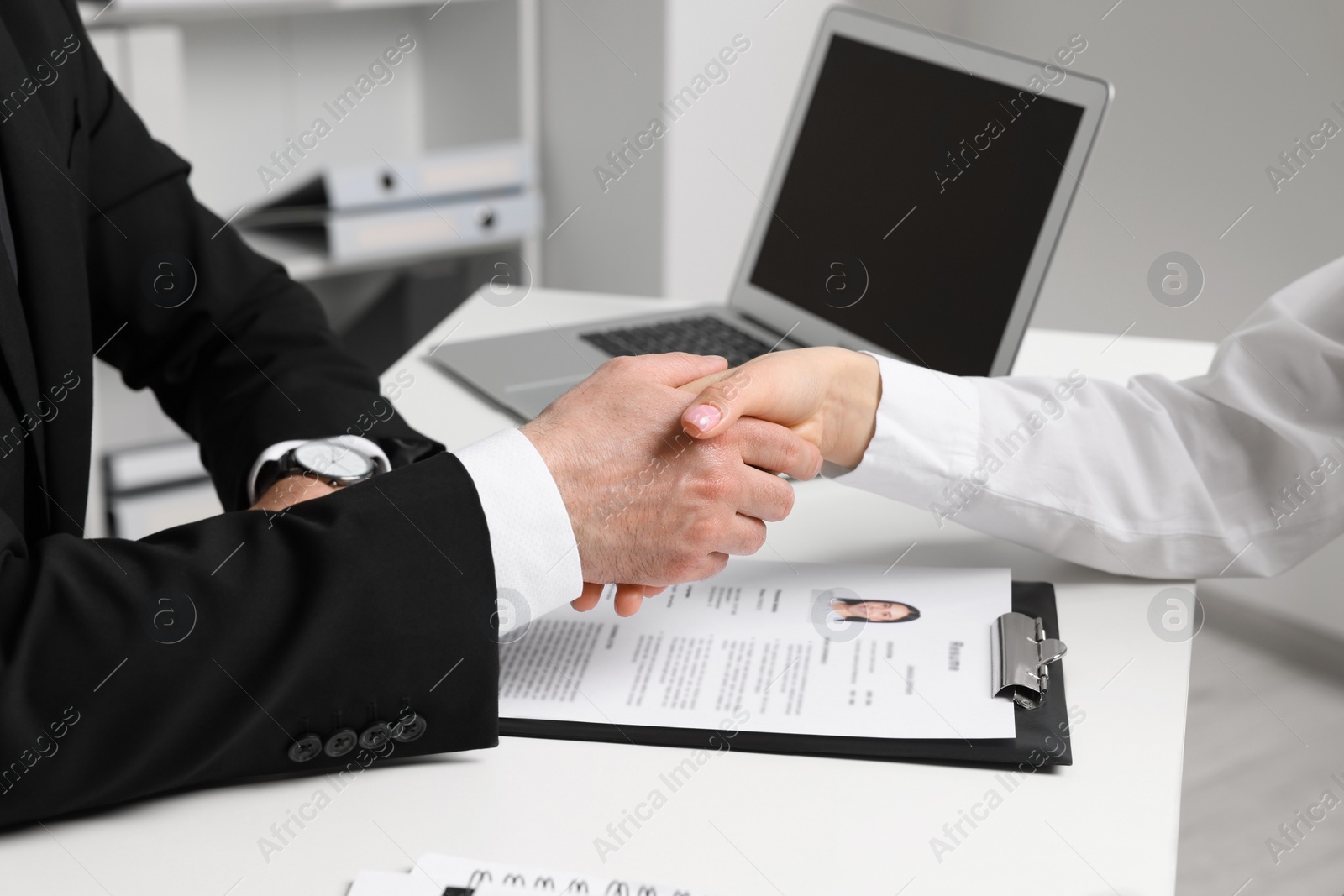 Photo of Human resources manager shaking hands with applicant during job interview in office, closeup