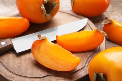 Delicious ripe persimmons and knife on wooden table