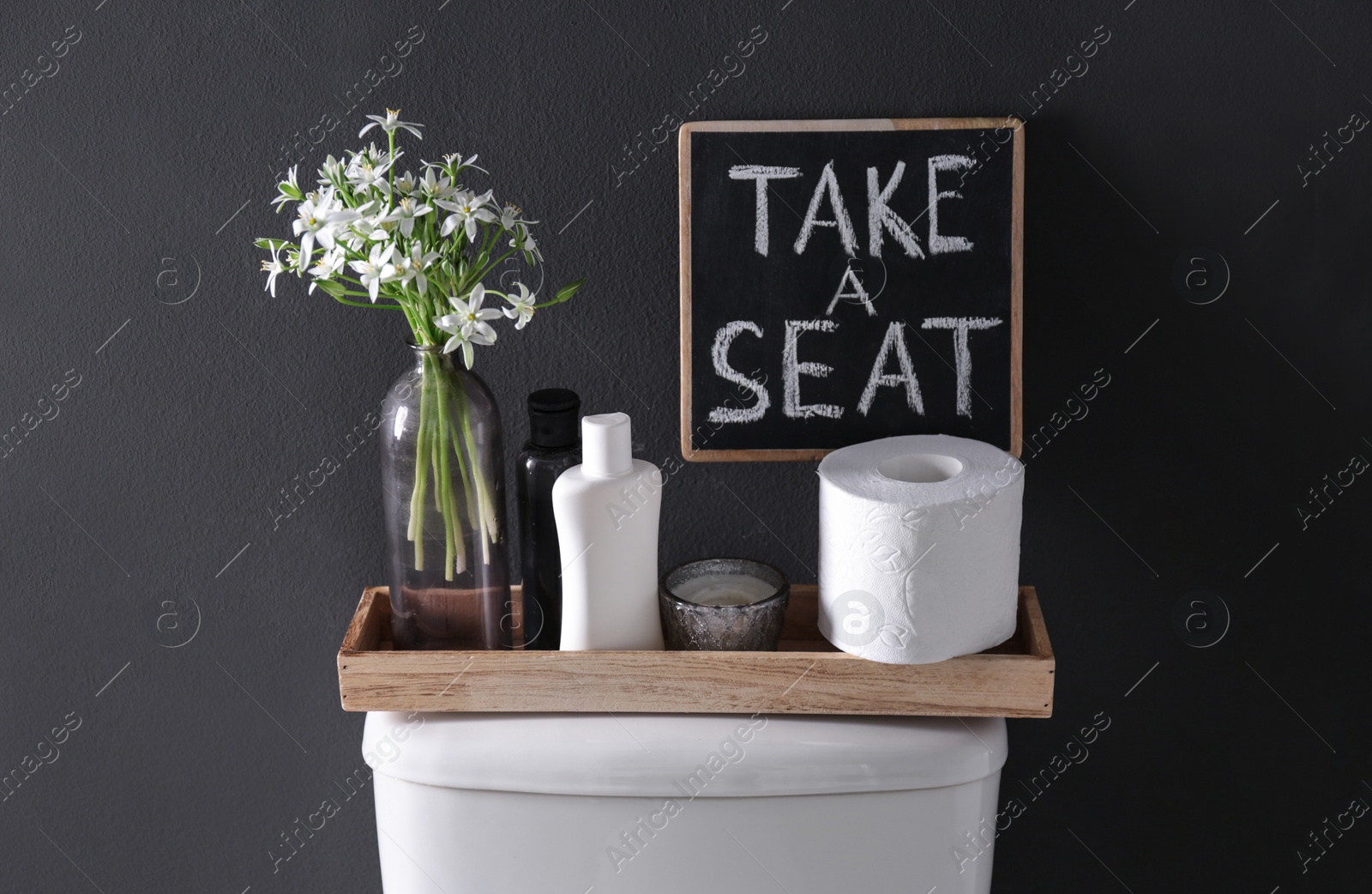 Photo of Decor elements, necessities and toilet bowl near black wall. Bathroom interior