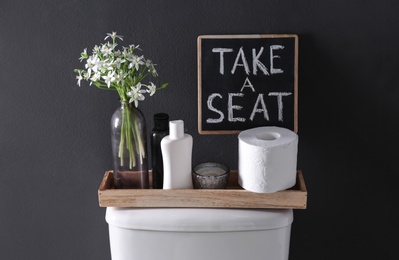 Photo of Decor elements, necessities and toilet bowl near black wall. Bathroom interior