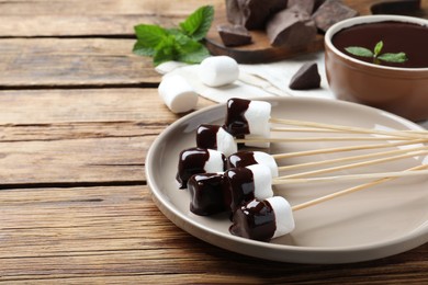 Photo of Delicious marshmallows covered with chocolate on wooden table