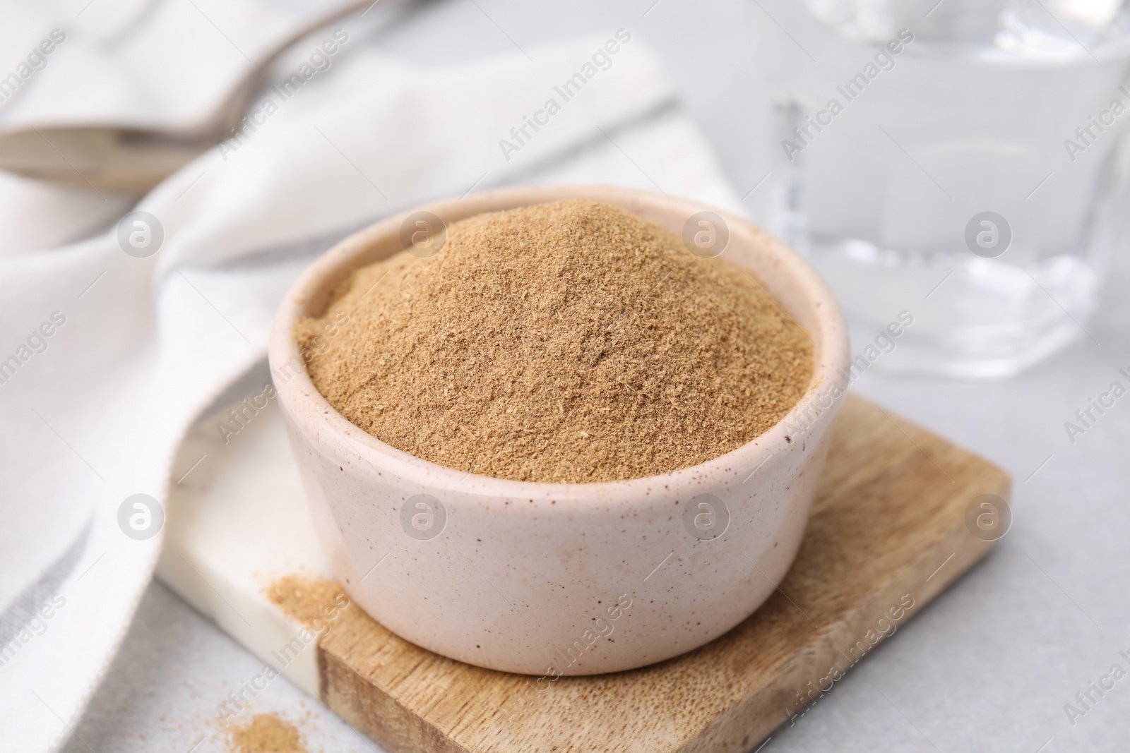 Photo of Dietary fiber. Psyllium husk powder in bowl on light grey table, closeup