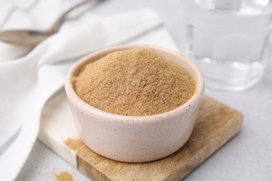 Photo of Dietary fiber. Psyllium husk powder in bowl on light grey table, closeup