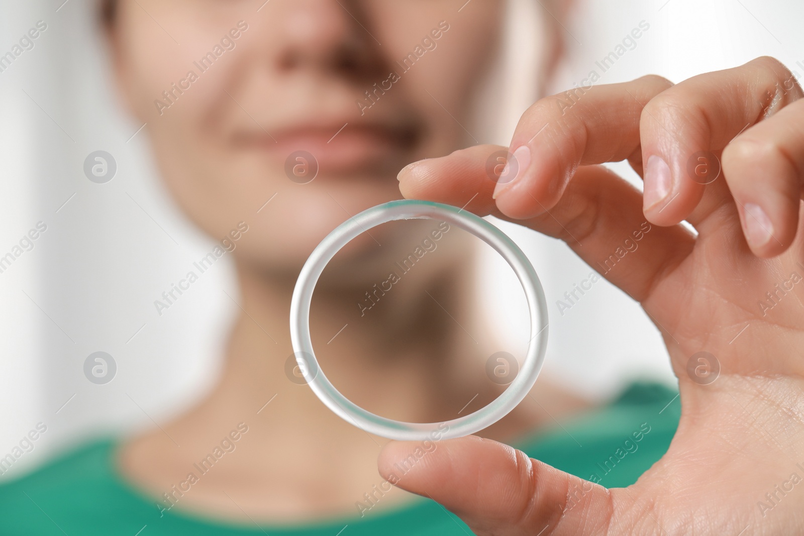 Photo of Woman holding diaphragm vaginal contraceptive ring on blurred background, closeup