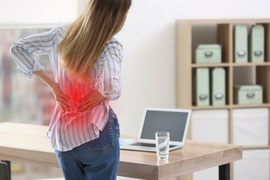 Image of Woman suffering from back pain in office. Symptom of bad posture