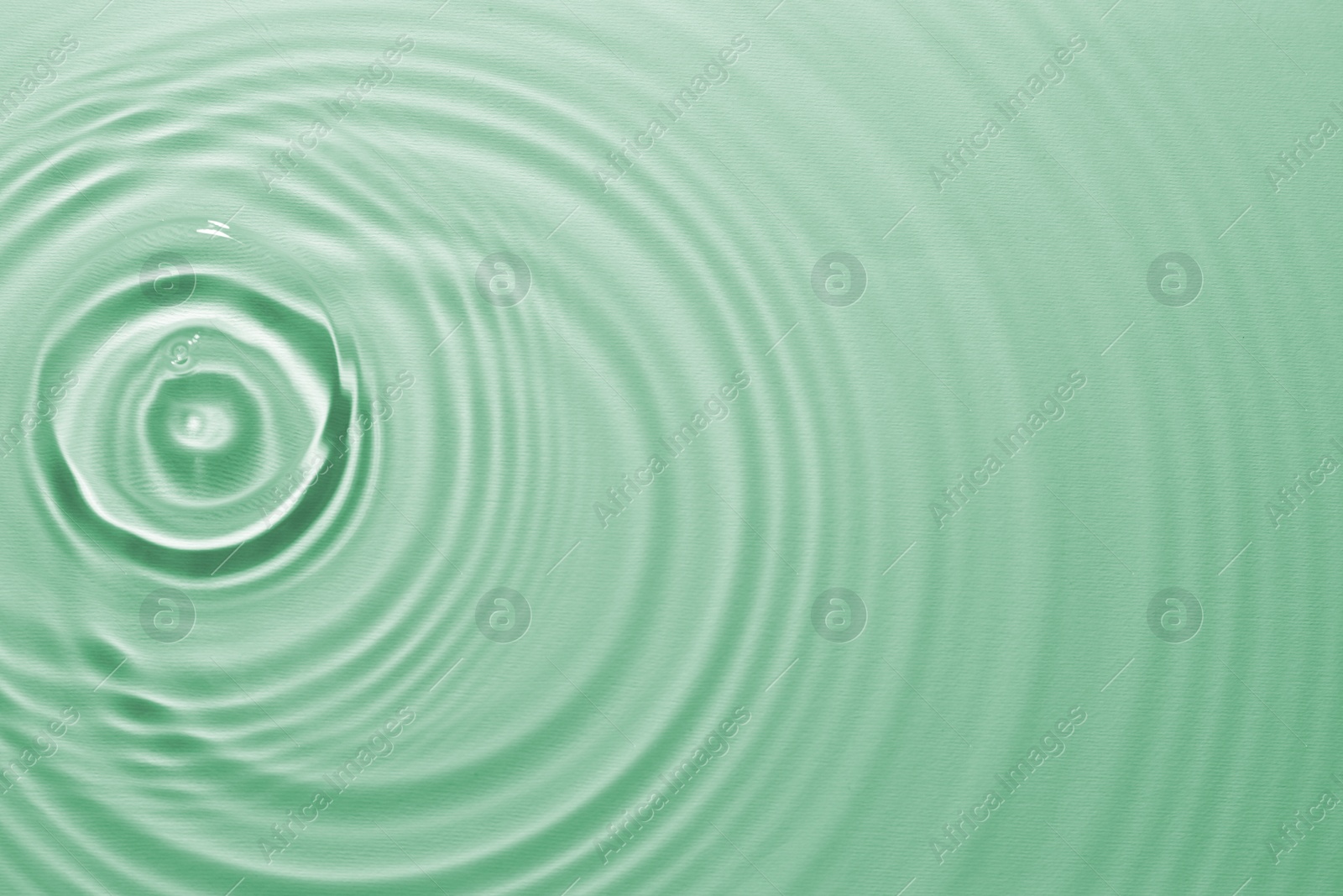 Image of Rippled surface of clear water on green background, top view