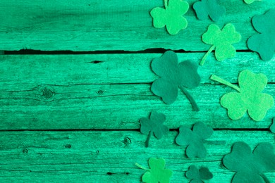 St. Patrick's day. Decorative clover leaves on green wooden background, top view. Space for text