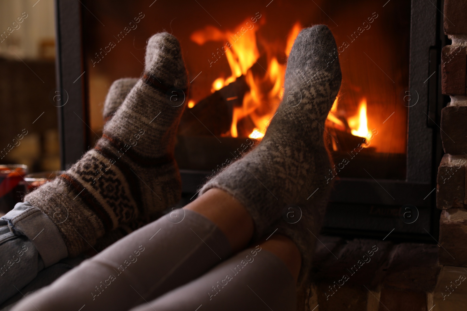 Photo of Couple resting near fireplace indoors, closeup. Winter vacation