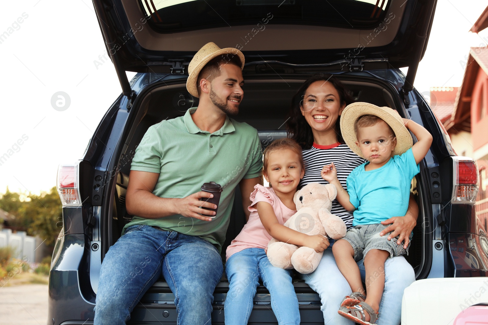 Photo of Happy family with suitcases near car in city street