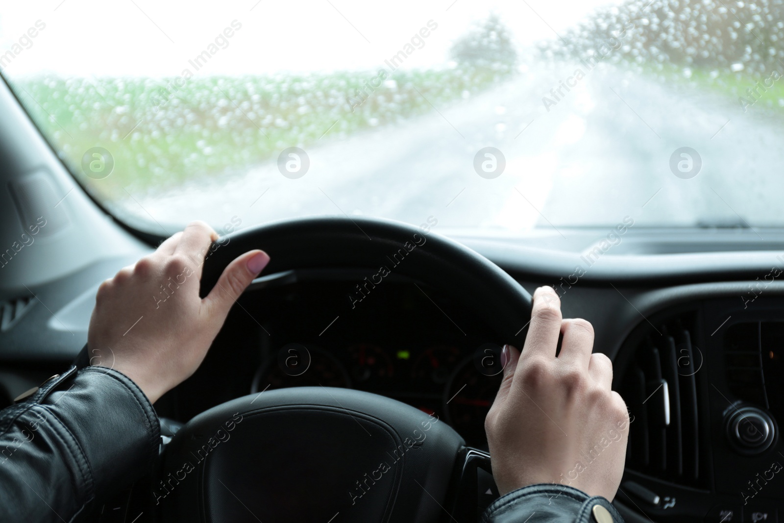 Photo of Woman driving car on rainy day, closeup of hands