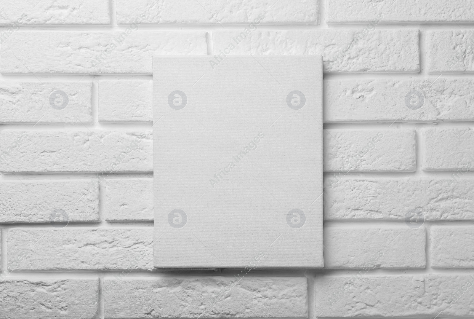 Photo of Blank canvas on white brick wall. Space for design