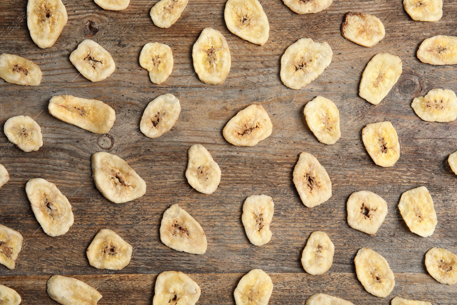 Photo of Flat lay composition with banana slices on wooden table. Dried fruit as healthy snack