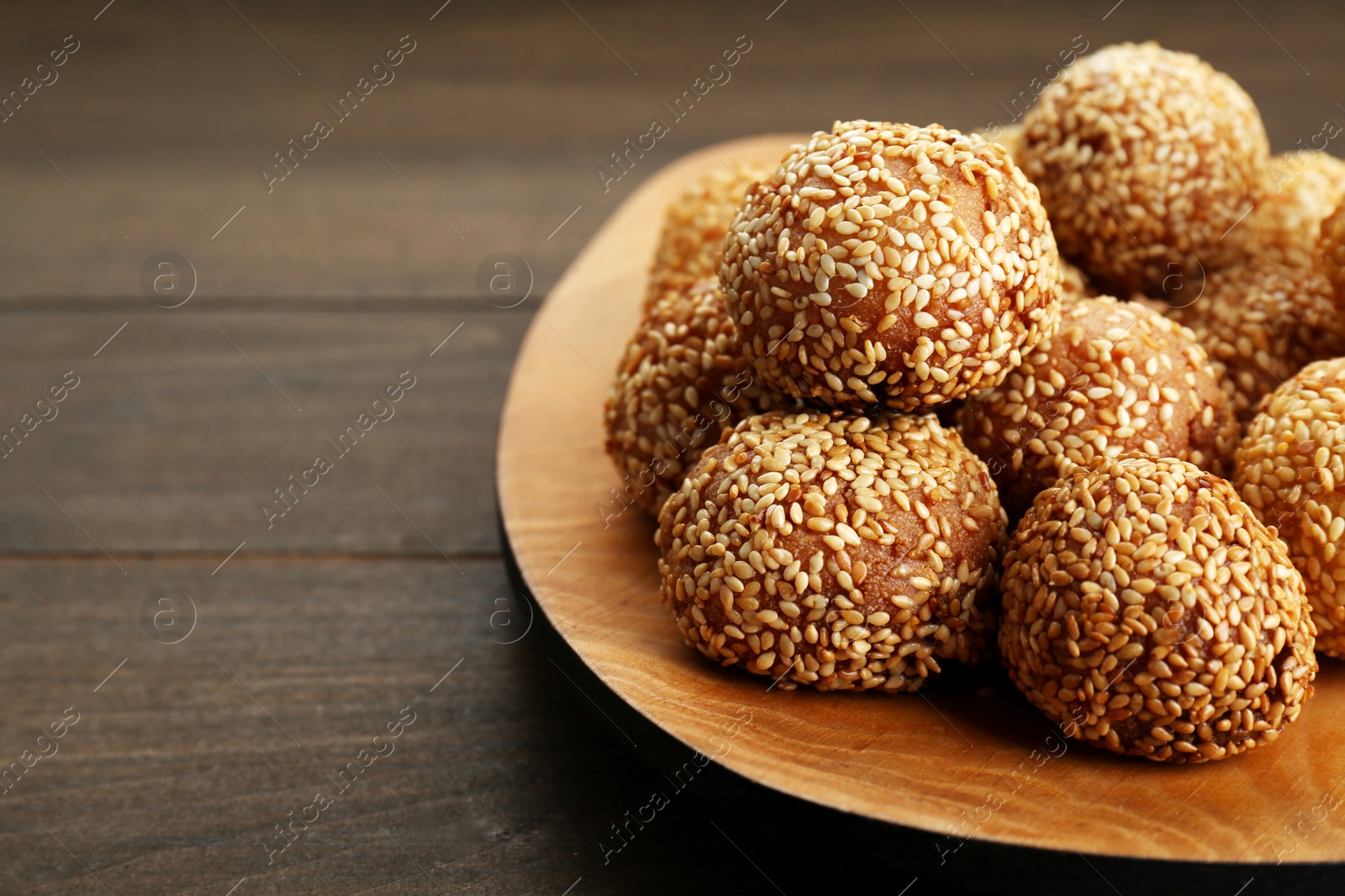 Photo of Many delicious sesame balls on wooden table, closeup. Space for text