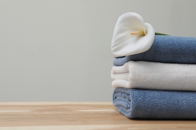 Photo of Stack of fresh towels with flower on table. Space for text