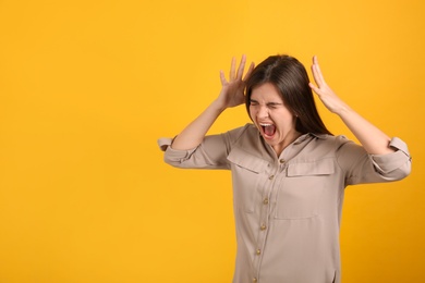 Portrait of stressed young woman on yellow background. Space for text