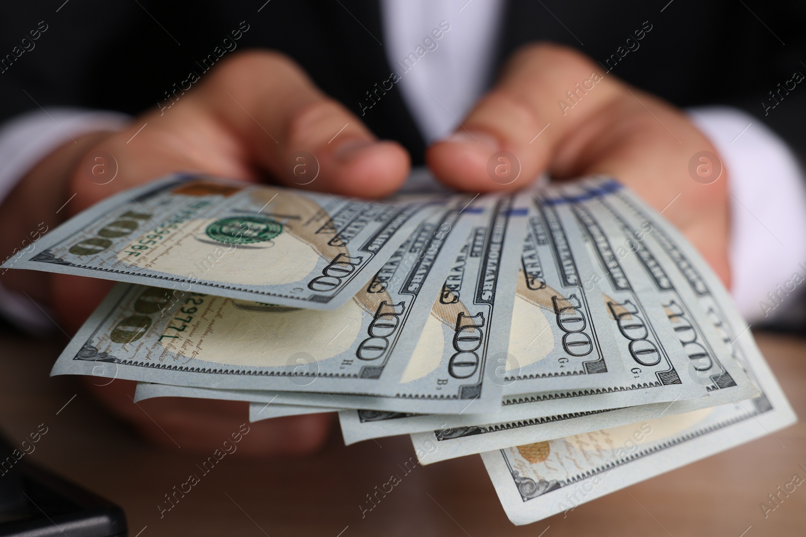 Photo of Money exchange. Man counting dollar banknotes at wooden table, closeup