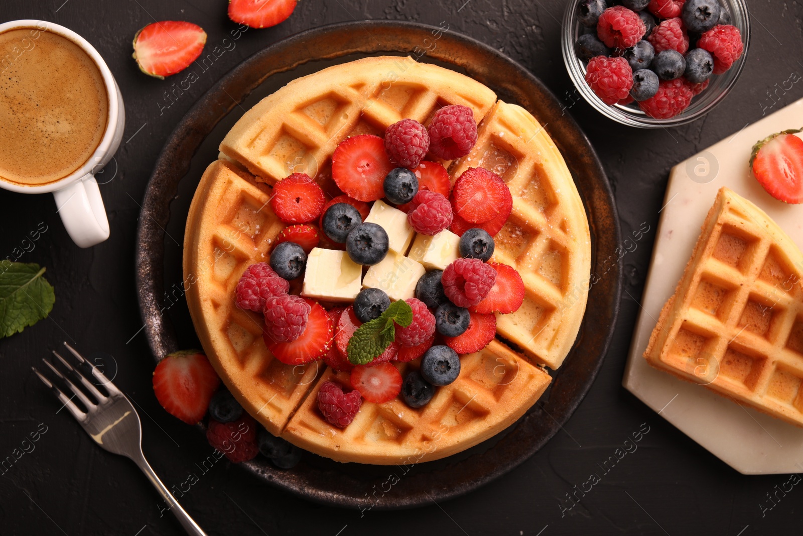 Photo of Tasty Belgian waffles with fresh berries served on black table, flat lay