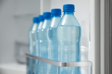 Photo of Many bottles with fresh water in fridge door bin, closeup