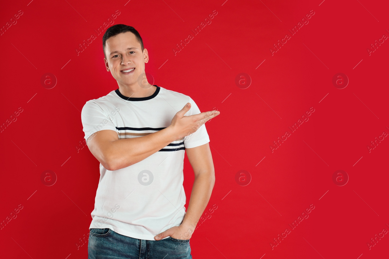 Photo of Happy handsome young man on red background. Space for text